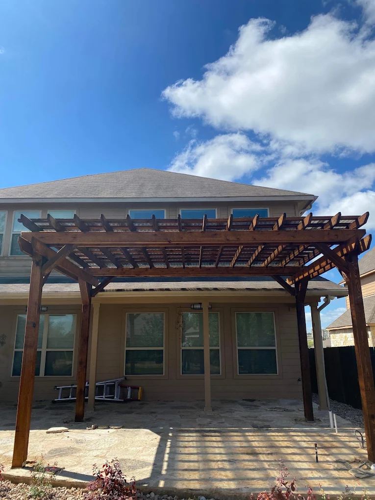 Dark-stained cedar pergola built over a back patio on a two-story house